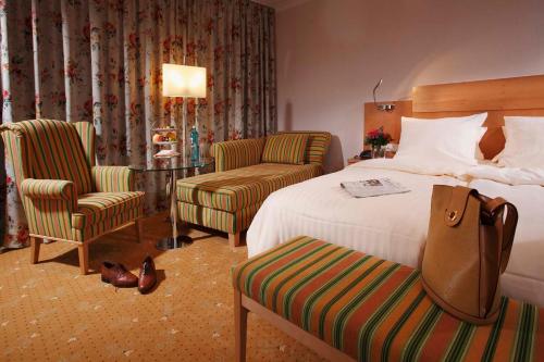 a hotel room with a bed and two chairs at Kurpark-Hotel in Bad Salzuflen