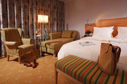 バート・ザルツフレンにあるKurpark-Hotelのベッド1台と椅子2脚が備わるホテルルームです。