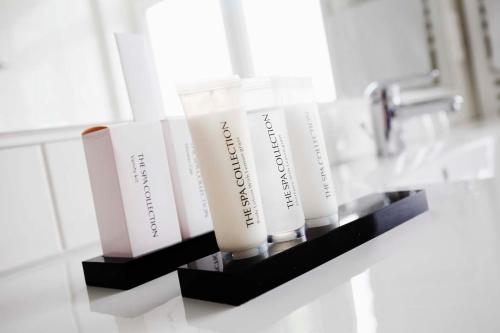 a shelf in a bathroom with four bottles of sunscreen at Kurpark-Hotel in Bad Salzuflen