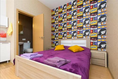 提比里斯的住宿－Pop Art Studio Apartment，一间卧室配有一张紫色床和一堵图片墙