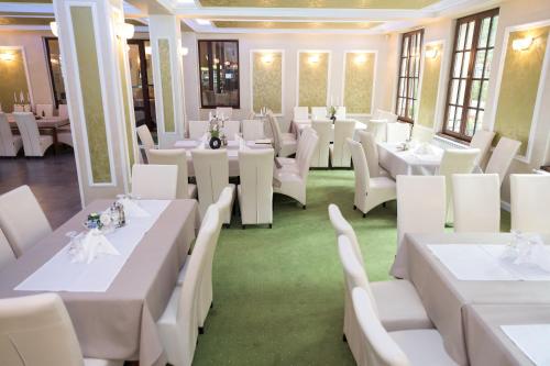 a dining room with white tables and white chairs at Complex Parc Pini Moinesti in Moineşti