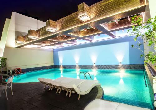 einen Pool in einem Hotel mit einer Bank davor in der Unterkunft Capitol Hotel Jumeirah Dubai in Dubai