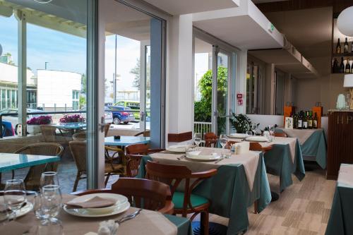 un restaurante con mesas, sillas y ventanas en Hotel Paradiso, en Senigallia