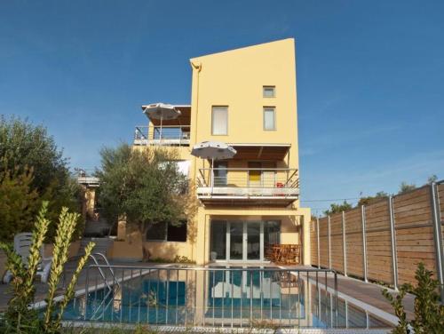 a yellow house with a swimming pool in front of it at Sorta Apartments in Kato Daratso