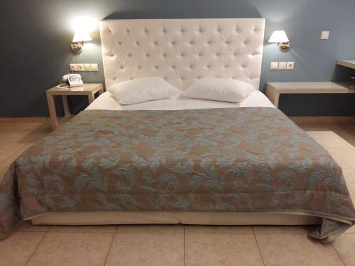 a bedroom with a large bed with a large headboard at Viaros Hotel Apartments in Tolo