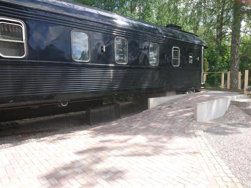 a black train is parked next to a platform at Silleruds Station in Årjäng