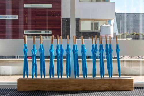 a group of blue umbrellas in a wooden display at de Baak Seaside in Noordwijk aan Zee
