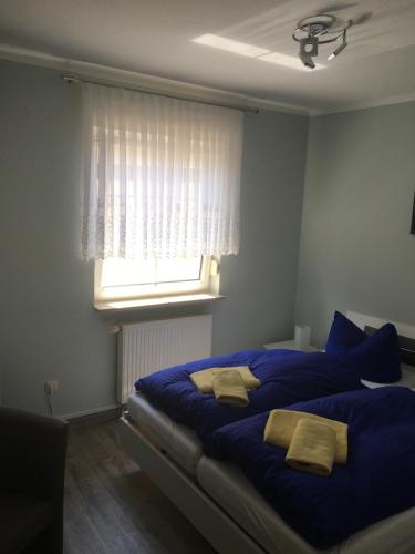 1 dormitorio con 1 cama grande con sábanas azules y ventana en Möllis Apartment am Jasmund-Nationalpark, en Lohme