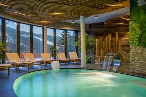 什平德萊魯夫姆林的住宿－奧林匹亞酒店，一个带椅子的房间的大型游泳池
