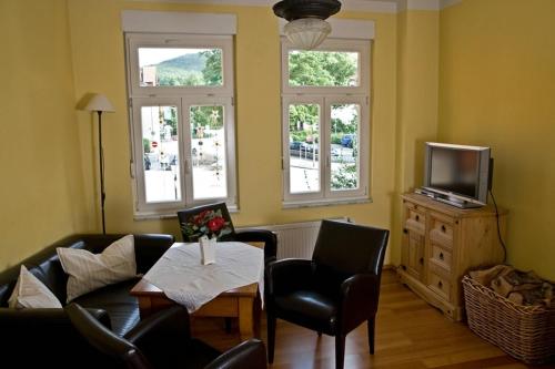a living room with a couch and chairs and a tv at Am Kleinsten Haus in Wernigerode