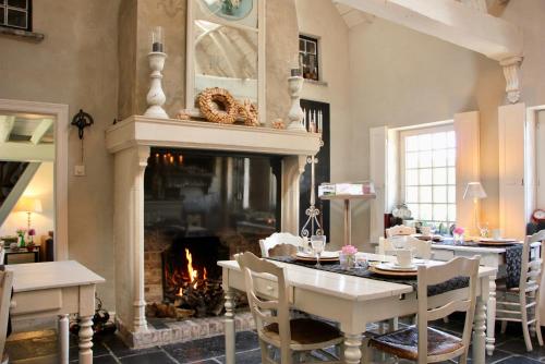a living room with a fireplace and a table and chairs at B&B Het Stille Genoegen in Brakel