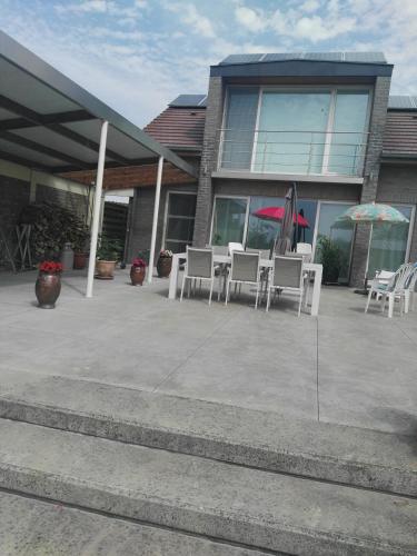 フールネにあるGuesthouse SiSaの建物の前に白いテーブルと椅子が備わるパティオ