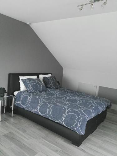 1 dormitorio con 1 cama con edredón y almohadas azules en Guesthouse SiSa, en Veurne