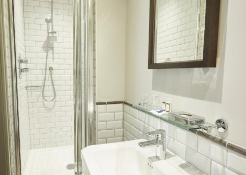 La salle de bains blanche est pourvue d'un lavabo et d'une douche. dans l'établissement Hartwood Hall by Greene King Inns, à Chorley