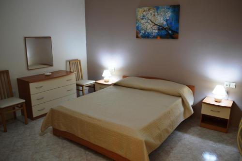 a bedroom with a bed and two tables and a dresser at The April Maisonette in Marsaskala