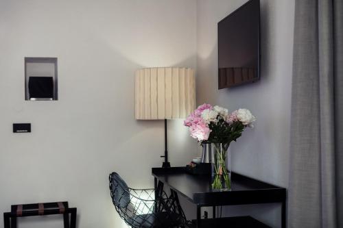 a vase of flowers on a table with a lamp at Kollmann Rooms and Apartments in Ljubljana