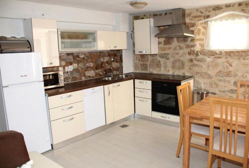 - une cuisine avec des appareils blancs, une table et des chaises dans l'établissement Vacation home Ania, à Prvić Luka