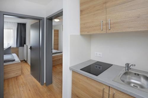 a kitchen with a sink and a room with a bed at easy sleep Apartmenthotel in Landshut