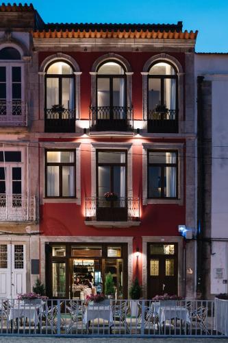 a red building with tables and chairs in front of it at Casa do Rio charm suites in Vila do Conde