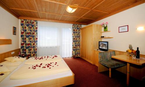 Habitación de hotel con cama, escritorio y mesa. en Ferienwohnungen Rahm, en Mayrhofen
