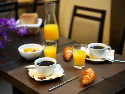 einen Tisch mit Tassen Kaffee, Croissants und Orangensaft in der Unterkunft Point du Jour in Casablanca