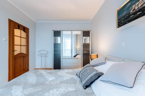 a white bedroom with a large bed and a bathroom at Apartament Morski in Kołobrzeg