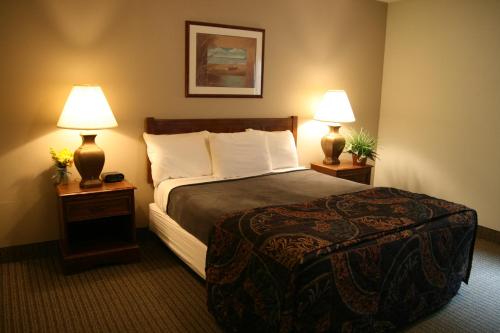 a hotel room with a bed and two lamps at Affordable Suites Jacksonville in Jacksonville