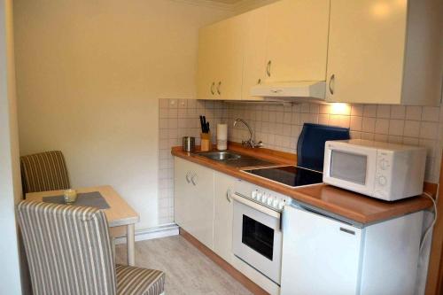 エッカーンフェルデにあるFerienhaus-Am-Strand-Haus-2の小さなキッチン(電子レンジ、テーブル付)