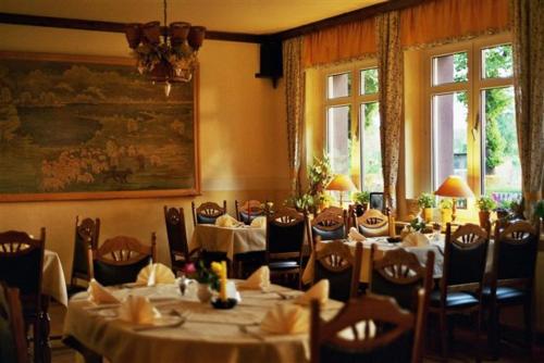 a dining room with tables and chairs and windows at Gasthaus Wagner in Golzow