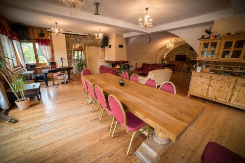 a large wooden table with pink chairs in a room at Chalet les Moineaux Chambres d'Hôtes in Jausiers