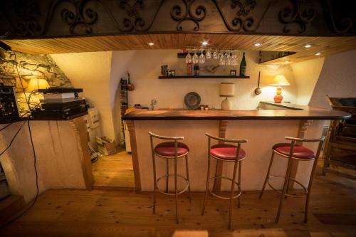 a kitchen with two bar stools at a counter at Chalet les Moineaux Chambres d'Hôtes in Jausiers