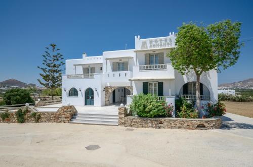 Una casa blanca con un árbol delante. en Agnadi Hotel, en Agia Anna de Naxos