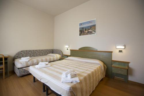 una camera d'albergo con due letti e un divano di Hotel Impero a Rimini