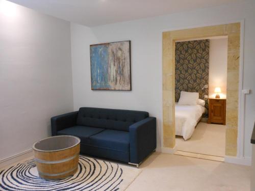 een woonkamer met een blauwe bank en een bed bij Les Logis du Roy in Saint-Émilion