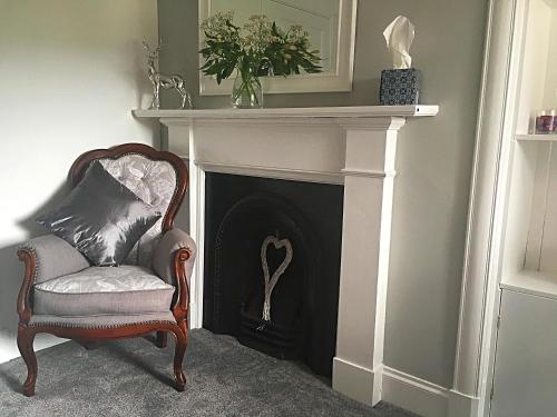 a chair sitting in front of a fireplace at Urrard B&B in Dingwall