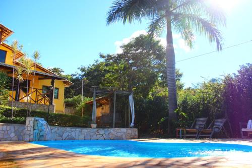 a palm tree and a house with a swimming pool at Pousada Luar do Cipó in Serra do Cipo
