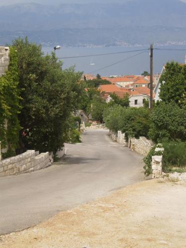 an empty road with trees and a town in the background at Apartmani Vesna Supetar in Supetar