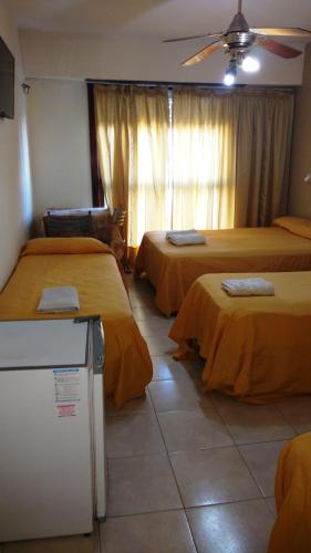 a hotel room with two beds and a refrigerator at San Remo World Hotel in San Clemente del Tuyú