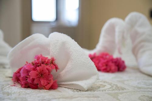 two white towels with pink flowers on a bed at Hotel La Campagnola in Capo Vaticano