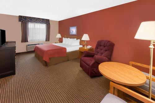 Una habitación de hotel con una cama, una silla y una mesa. en Super 8 by Wyndham St. Ignace, en Saint Ignace