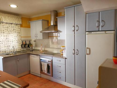 チピオナにあるLa Casa del Camaleonのキッチン(白いキャビネット、冷蔵庫付)
