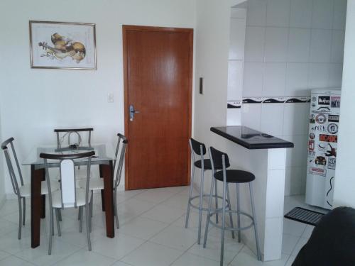 a kitchen with a table and chairs and a wooden door at Apartamento Praia Grande Ocian in Praia Grande