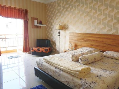 ein Schlafzimmer mit einem Bett, einem Stuhl und einem Fenster in der Unterkunft Apartemen MTC 623 in Manado