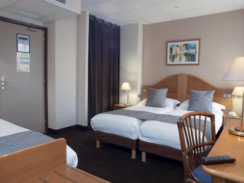 a hotel room with two beds and a desk at Hôtel Esprit d'Azur in Nice