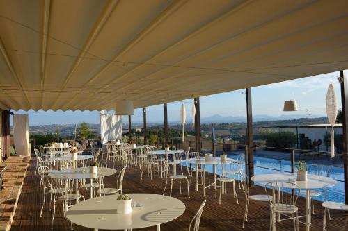 un restaurante con mesas y sillas y una piscina en Solea Relais di Charme- Adults only, en Trecastelli