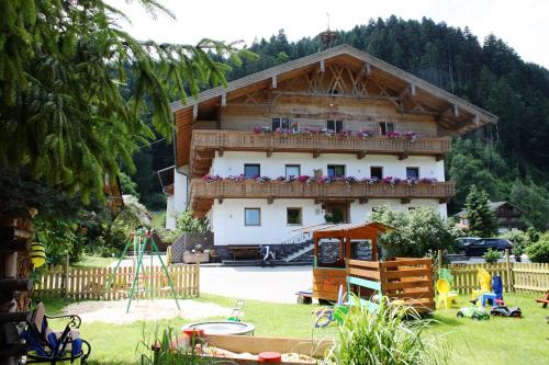 ein Haus mit einem Balkon und einem Spielplatz davor in der Unterkunft Ferienhof Kampfl in Fügen