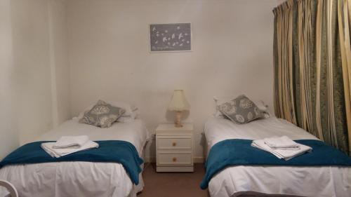 two twin beds in a room with a night stand at Clarence Road Apartment in Gosport