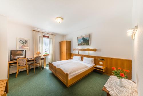 a bedroom with a bed and a desk and a television at Hotel Goldener Sternen in Konstanz