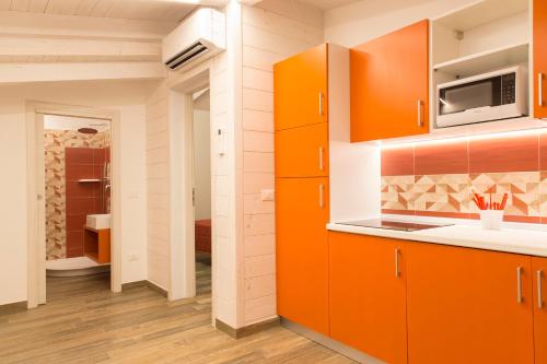 カーポ・ヴァチカーノにあるMarinella Beach Apartmentのキッチン(オレンジ色のキャビネット、電子レンジ付)