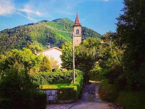 a building with a clock tower in front of a mountain at Belvilla by OYO Casa Via Pieve in Ponte della Venturina
